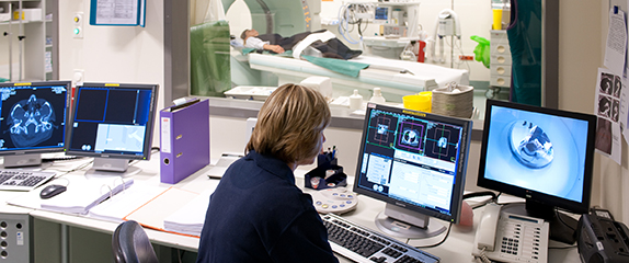 Mitarbeiterin vor dem Monitor mit Patient in der Radiologie